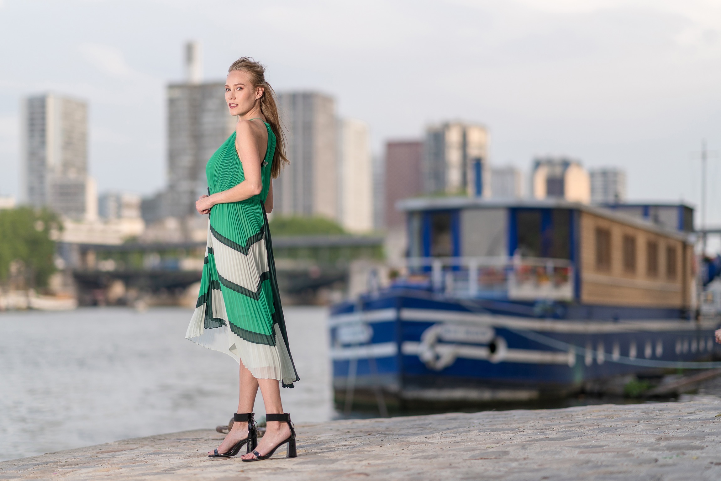 Portrait dramatique sur les rives de la Seine avec un restaurant sur un bateau et la ville nouvelle en arrière-plan.